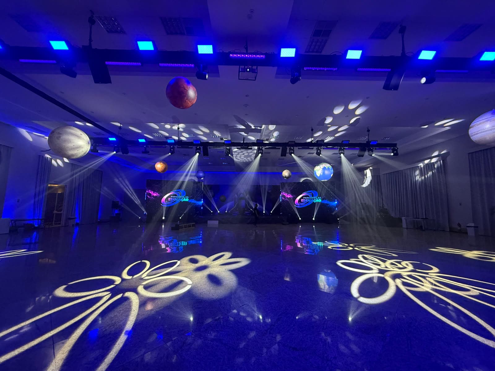 Evento real: salão montado com moving heads, gobos no piso e painéis de LED